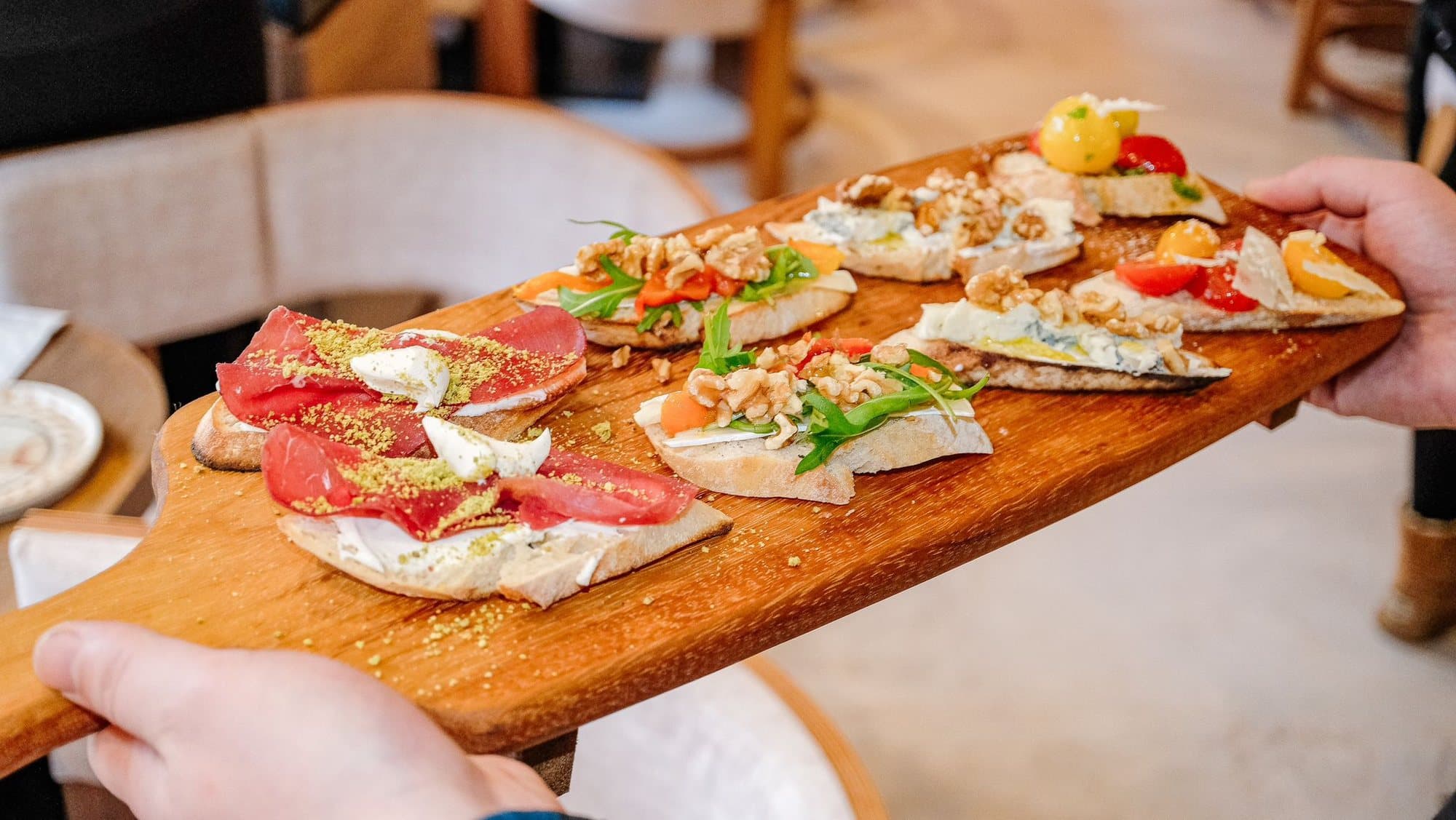 A mixed bruschetta board carried to the table