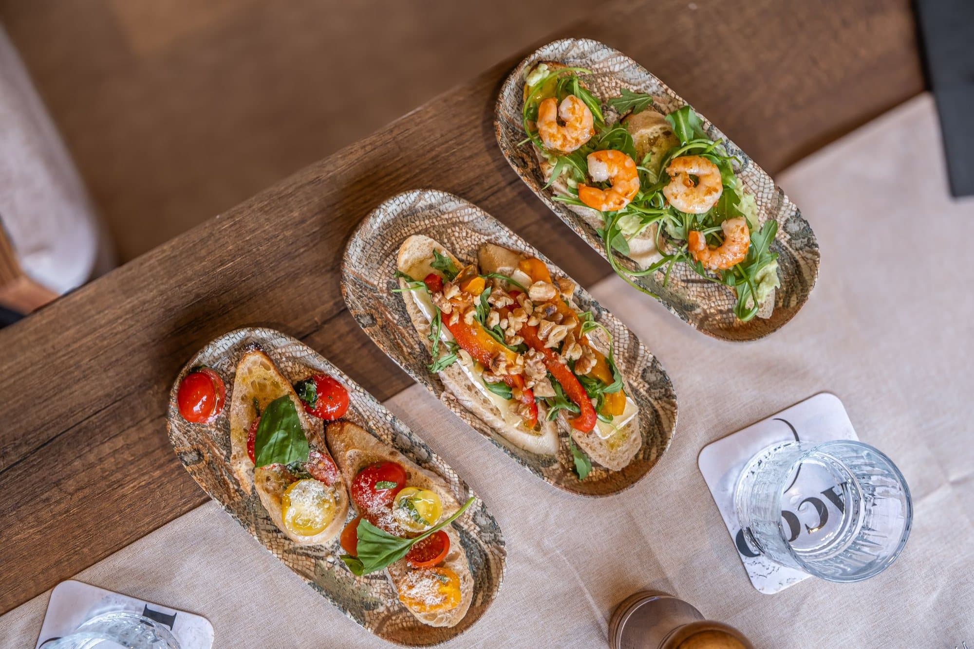 Three bruschetta on slate boards, dressed with tomatoes and rocket